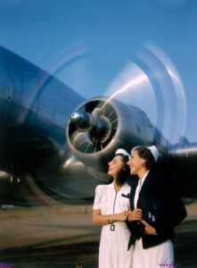 Two young women stand near a turning aircraft propeller, 1940.